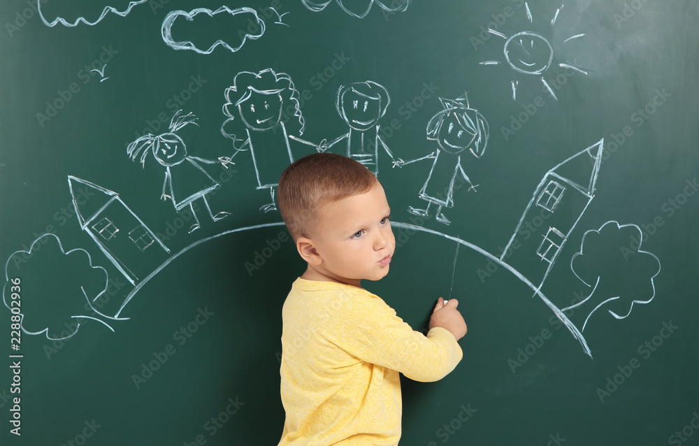 Little child drawing family with white chalk on blackboard Little child drawing family with white chalk on blackboard