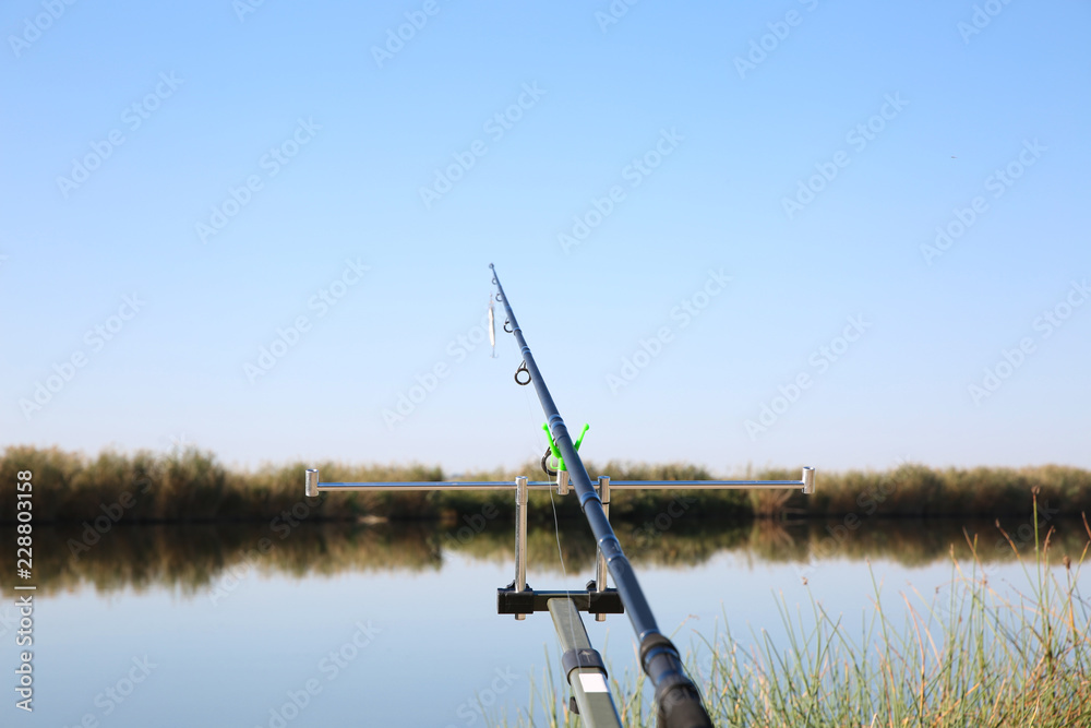 Fishing rod at riverside on sunny day