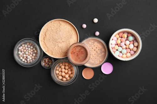 Flat lay composition with various makeup face powders on black background