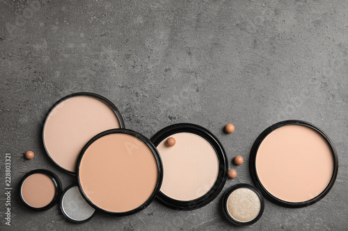 Flat lay composition with various makeup face powders on gray background. Space for text