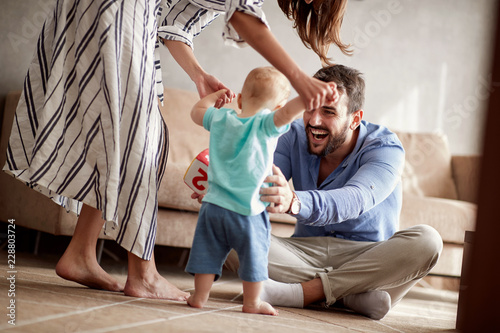 Tableau sur toile happy couple mother and father playing with a baby at home.