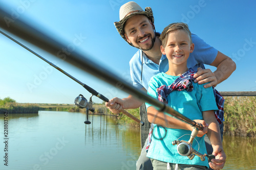 Father and son fishing together on sunny day. Space for text