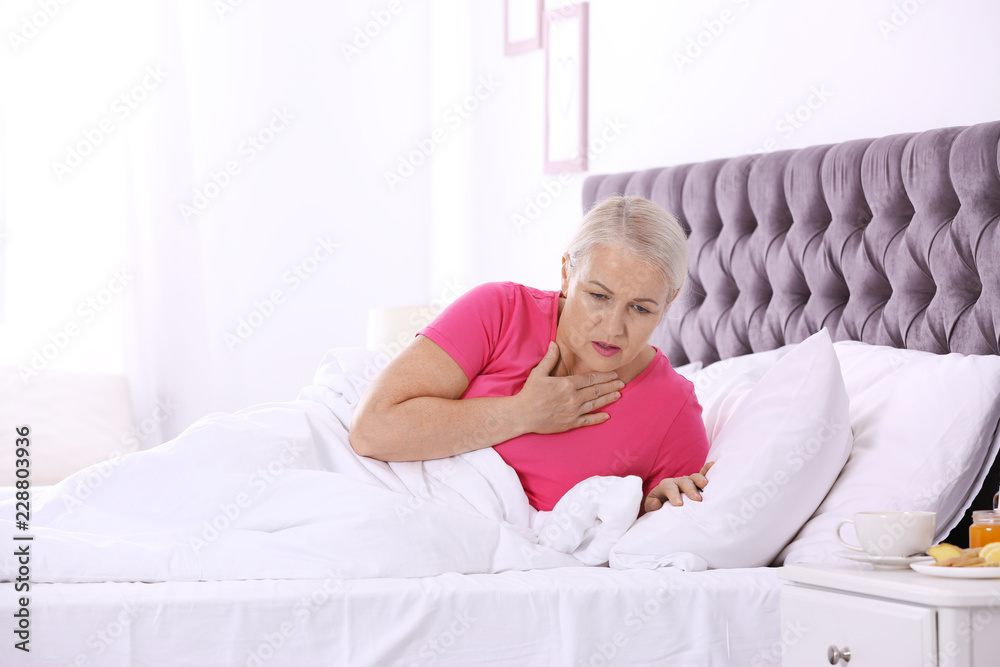 Ill mature woman suffering from cough in bed