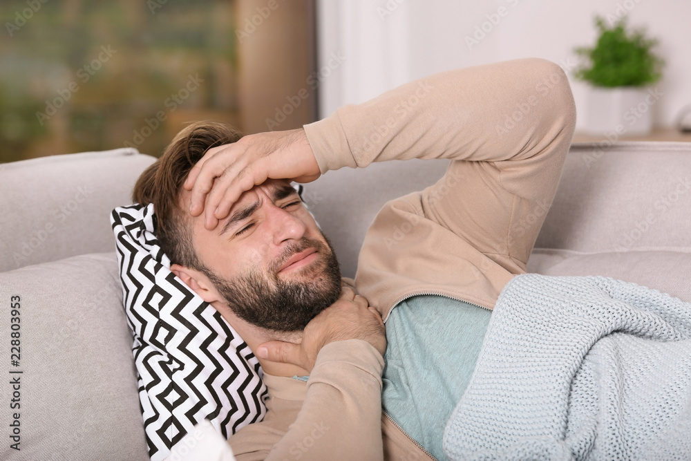 Ill man suffering from cough on sofa at home Ill man suffering from cough on sofa at home