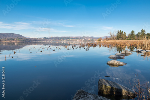 Lake Comabbio, beautiful natural lake of glacial origin, in northern Italy. View from the bike path at Varano Borghi towards the town of Ternate. Beautiful day of late autumn