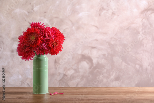 Fototapeta Naklejka Na Ścianę i Meble -  Beautiful dahlia flowers in vase on table against color background. Space for text