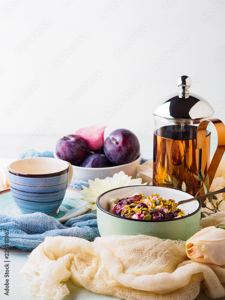 Breakfast with bowl of fresh quark, berries, seeds. Table setting with coffee and flowers