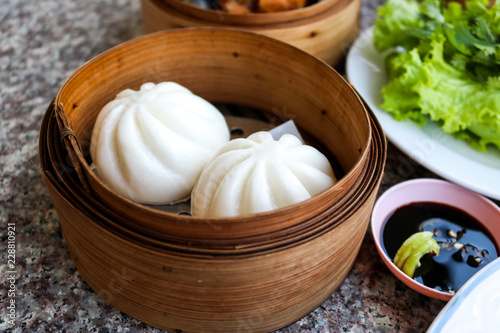 Steamed white flour dumplings placed in a wooden tray on the table.