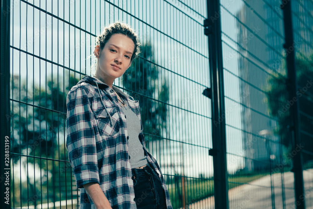Young lady looking confident while standing next to the chain link fence