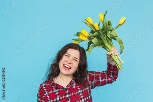Laughing young caucasian woman with bouquet of tulips on blue background. photo