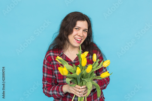 Laughing young caucasian woman with bouquet of tulips on blue background. photo
