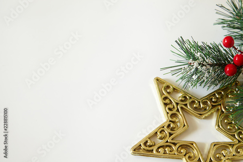 Fir tree branches, red berries, golden decorations on white background. Christmas backdrop.