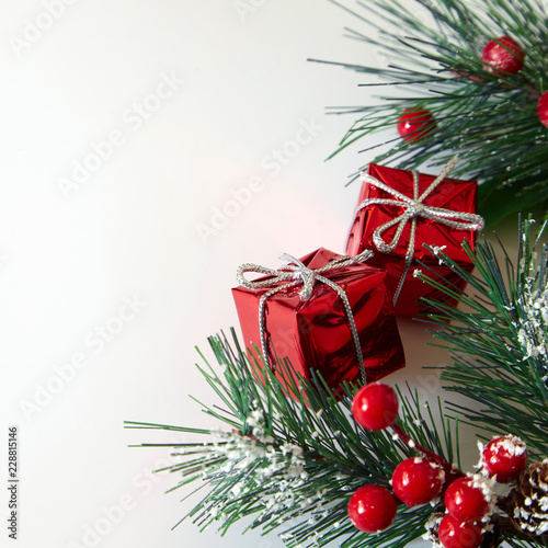 Christmas tree branches, red berries and gifts on white backgrounds.