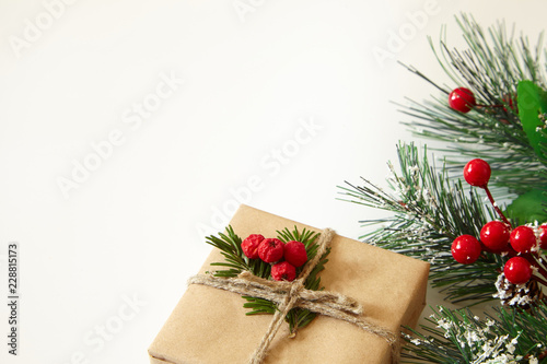 Christmas tree branches, red berries and gift on white backgrounds.