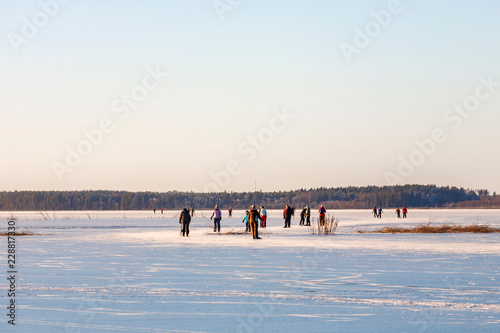 People ice Skating at a winter day on a natural lake