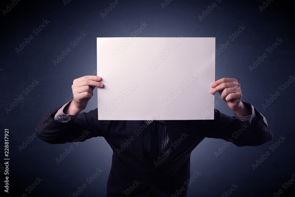 Young businessman hiding behind a blank piece of paper Young businessman hiding behind a blank piece of paper