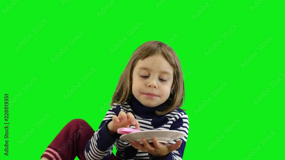 Little charming girl eating glazed delicious donut on a green background. Little charming girl eating glazed delicious donut on a green background.