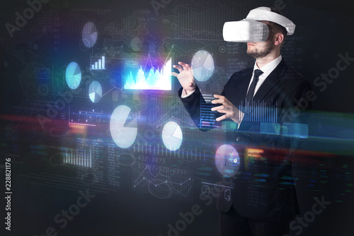 Elegant businessman in DJI goggles handling 3D reports and charts around him 
