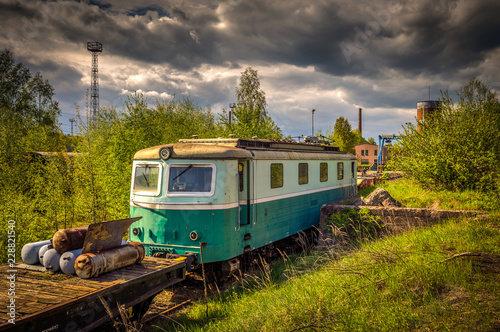 Old locomotive Skoda 53E in train cemetery in the summer with green grass and trees in the background and great cloudy sky
