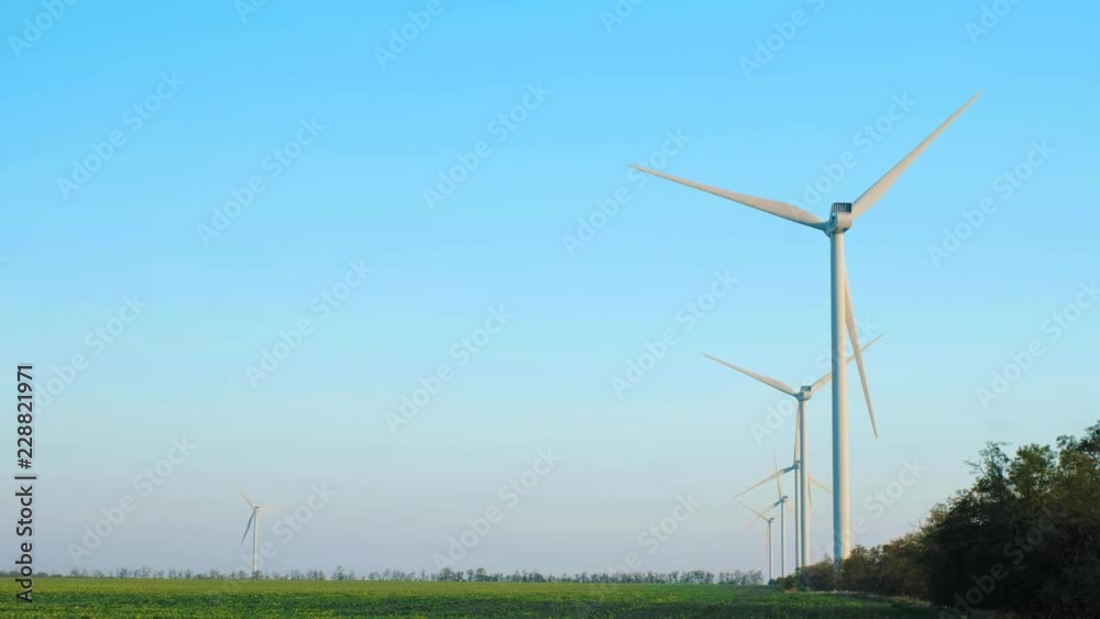 A view of calmly spinning wind generators in a field A view of calmly spinning wind generators in a field