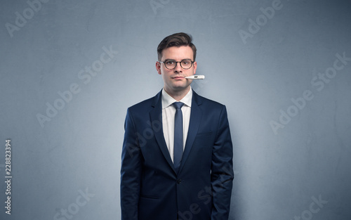 Young tired businessman with thermometer and copy space 