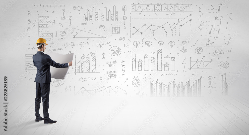 Engineer with construction helmet holding a plan and standing with graphs, charts and reports on the background Engineer with construction helmet holding a plan and standing with graphs, charts and reports on the background