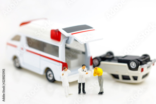 Miniature people: Doctor and patient standing with ambulance. Health care and emergency concept.