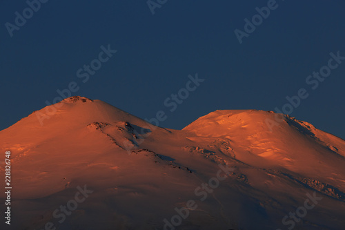 Dawn over the snow-capped peaks of Mount Elbrus. A closeup of a mountain range in the North Caucasus in Russia.