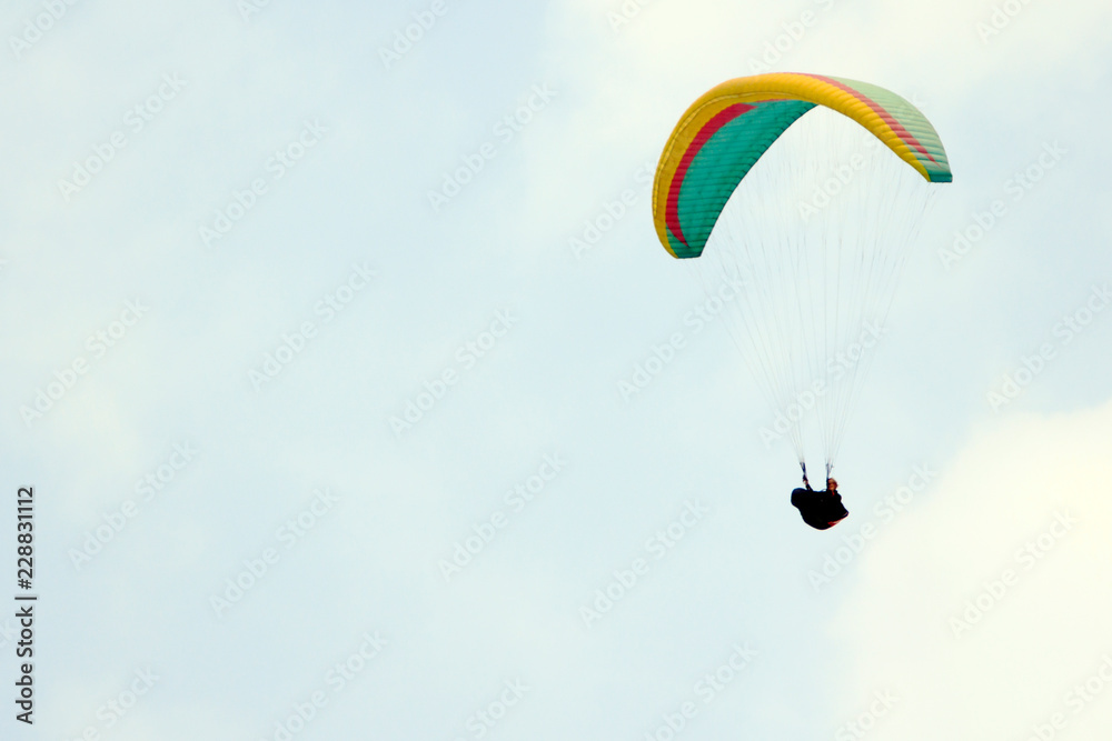 Paragliding over the mountains against clear blue sky Paragliding over the mountains against clear blue sky