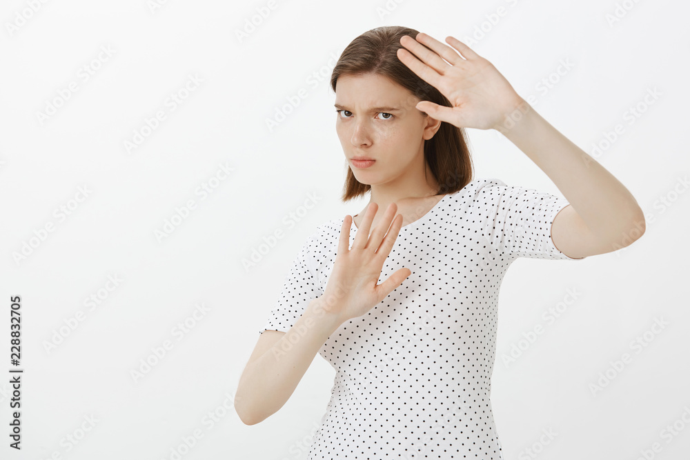 Girl gonna protect herself from paparazzi. Portrait of intense angry and annoyed woman, covering body with raised palms, staring pissed and displeased at camera, defending from cameras over grey wall Girl gonna protect herself from paparazzi. Portrait of intense angry and annoyed woman, covering body with raised palms, staring pissed and displeased at camera, defending from cameras over grey wall