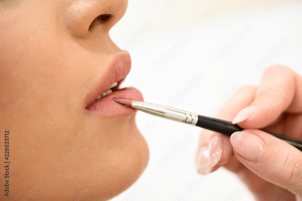 Makeup artist making up lips of an African young woman