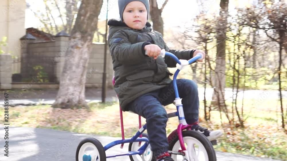 Cute kid child, boy, rides with a tricycle in the park Cute kid child, boy, rides with a tricycle in the park