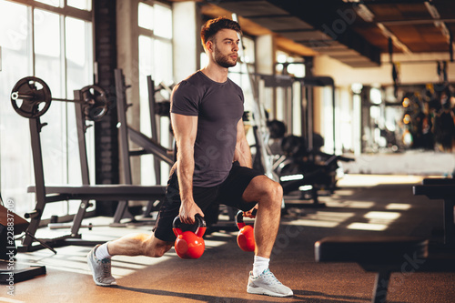 Handsome man legs workout with kettlebell in the gym
