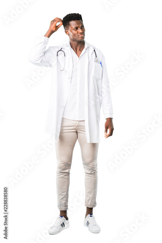 Full body of African american doctor having doubts and with confuse face expression while scratching head on white background