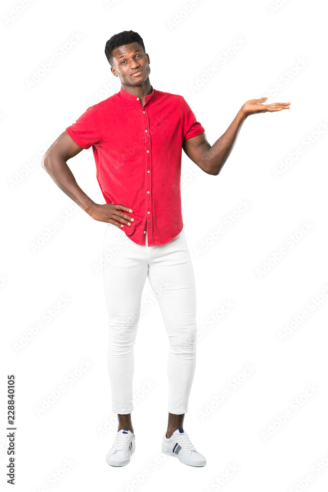 Full body of Young african american man holding copyspace imaginary on the palm to insert an ad on white background Full body of Young african american man holding copyspace imaginary on the palm to insert an ad on white background