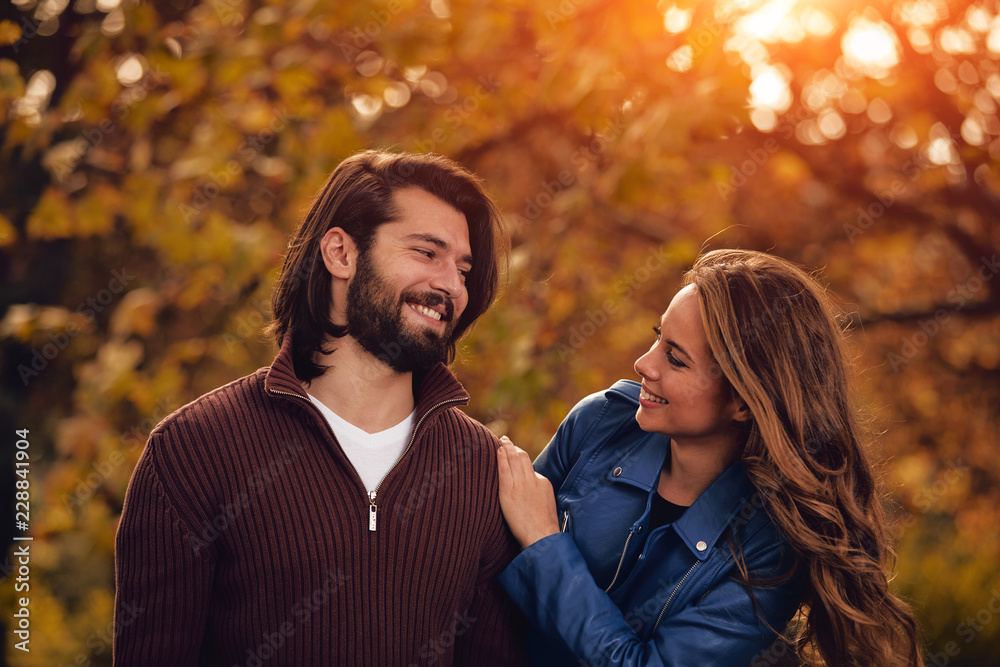 Fototapeta premium Couple in autumn season colored park enjoying outdoors.