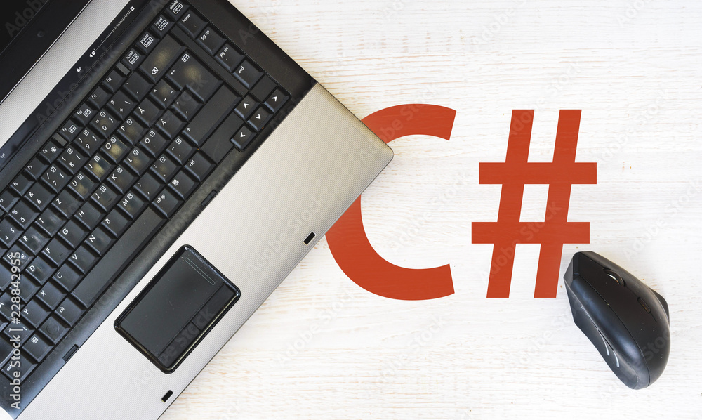C sharp programming language,. laptop and vertical mouse on desk with ...