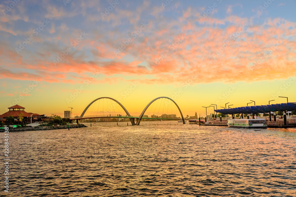 Scenic landscape of Elizabeth Quay Bridge on Swan River in Elizabeth Quay marina. The arched bridge is a new tourist attraction in Perth, Western Australia. Sky with red clouds of sunset.