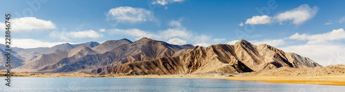 Panorama of pamir mountains near Lake Karakul (Xinjiang Province, China, Asia). Beautiful rough landscape, clear and clean blue sky with clouds. Along the Karakorum Highway. Space, wilderness, freedom photo