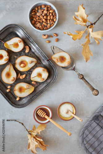 Flat lay with a tray of baked pears with caramelized nuts on gray concrete background