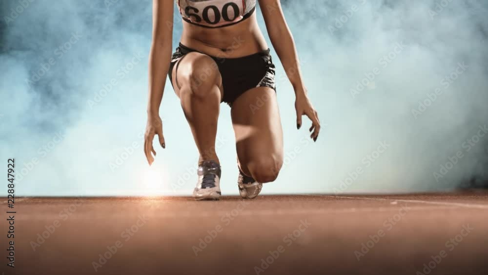 Asian Athlete ready to start. Young female runner preparing for blasting off in mist on sports track of stadium, training before competition