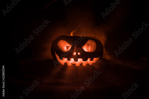 Halloween pumpkin smile and scrary eyes for party night. Close up view of scary Halloween pumpkin with eyes glowing inside at black background.