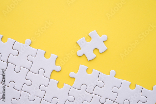 Cuadro en lienzo Unfinished white jigsaw puzzle on yellow background