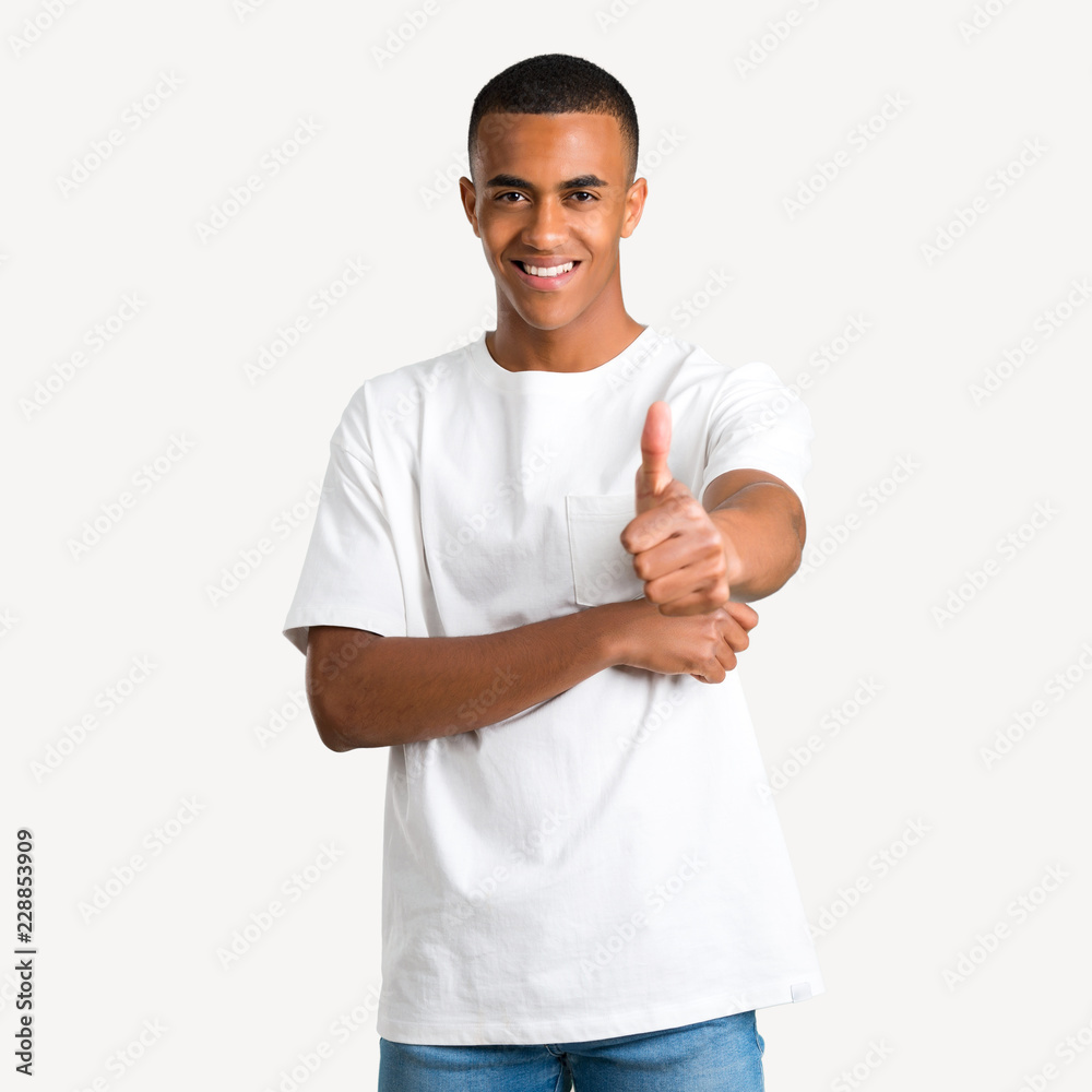 Young african american man giving a thumbs up gesture and smiling because something good has happened on isolated background Young african american man giving a thumbs up gesture and smiling because something good has happened on isolated background