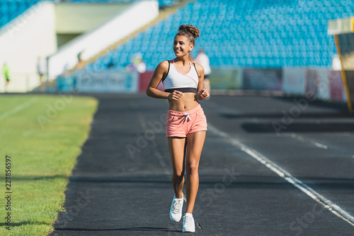 Good-looking girl running marathon with smile. Outdoor shot of amazing female model doing cardio in morning