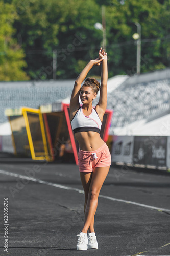 Image of happy beautiful young sports woman outdoors on stadium posing. horizontal photo