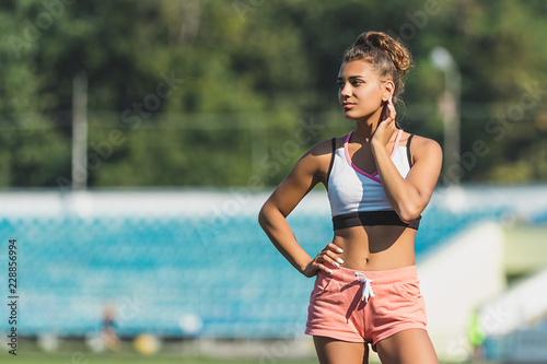 Fashionable stylish woman in sportwear posing on empty stadium