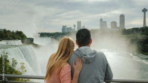 A young multi-ethnic couple admires a beautiful view of the Niagara Falls. Travel in America and Canada