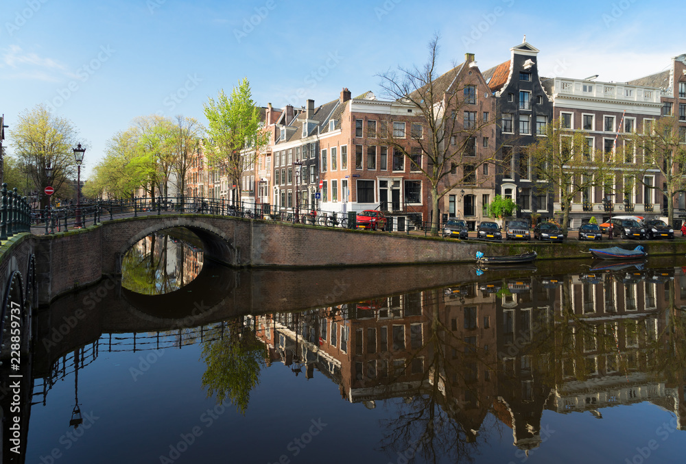Historical houses and bridge over canal with mirror reflections, Amsterdam, Netherlands