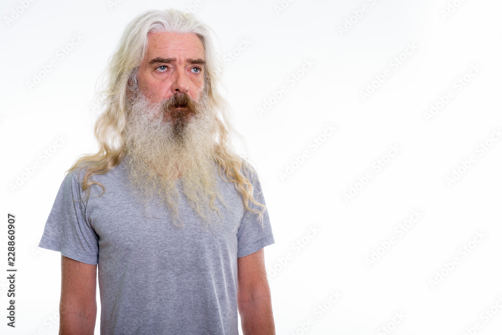 Studio shot of senior bearded man thinking while looking at dist Studio shot of senior bearded man thinking while looking at dist